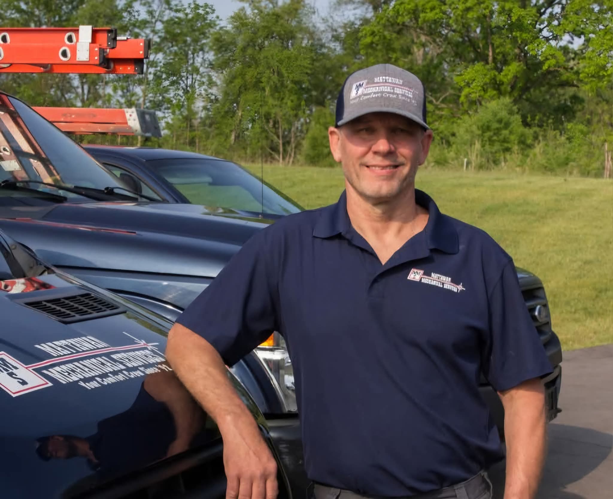 Contractor smiling standing in front of their company car.